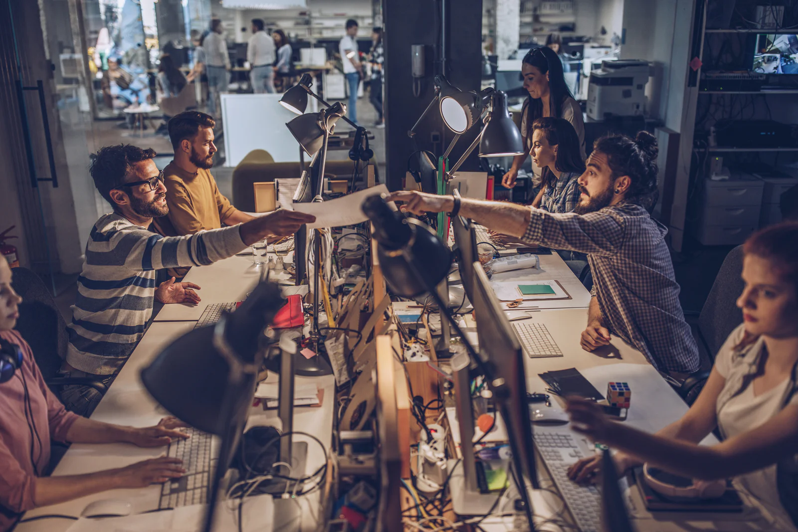 Large group of graphic designers cooperating while working on computers at corporate office.