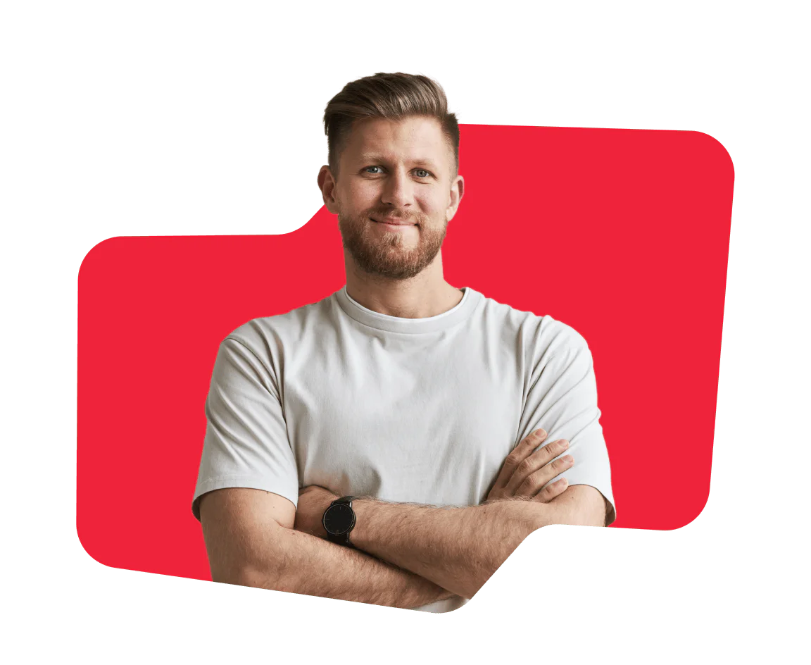 Smiling man with a beard, arms crossed, wearing a white t-shirt against a red abstract background.