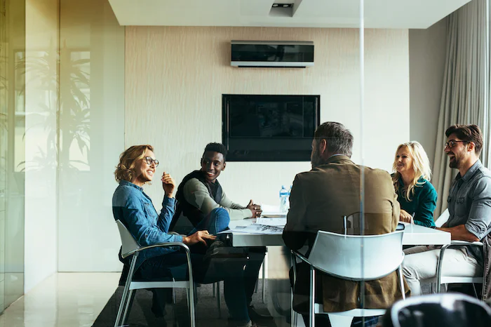 Five people sitting around a conference table having a meeting in a bright, modern office.