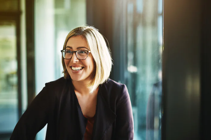 Woman with glasses smiling indoors in a professional setting